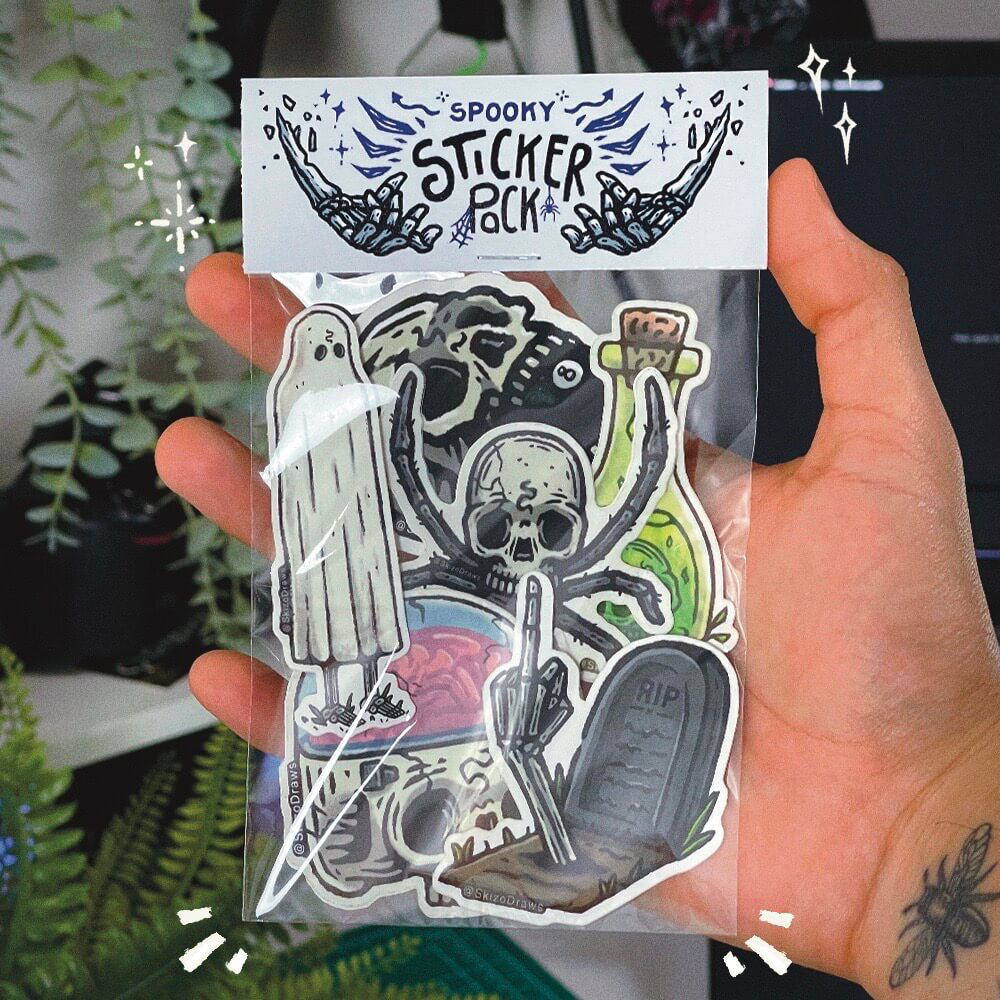 Mano che tiene un pacchetto di adesivi a tema spaventoso in stile cartoon, con un cartellino di intestazione con la scritta “SPOOKY STICKER PACK”, su uno sfondo di piante.