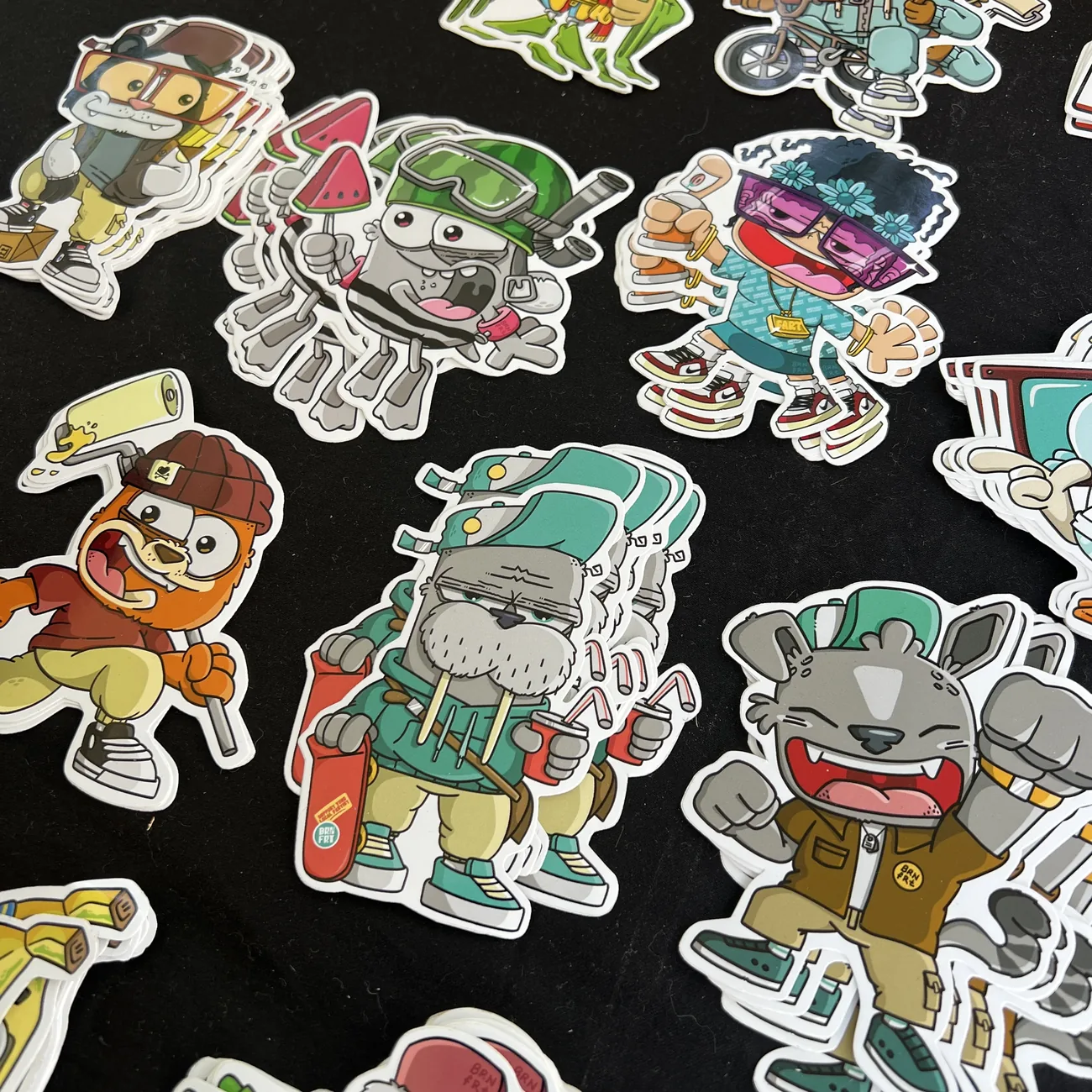 Adesivi sagomati Brainfart x StickerApp con personaggi dei cartoni in streetwear, tra cui un tricheco con lo skateboard e un gatto sorridente
