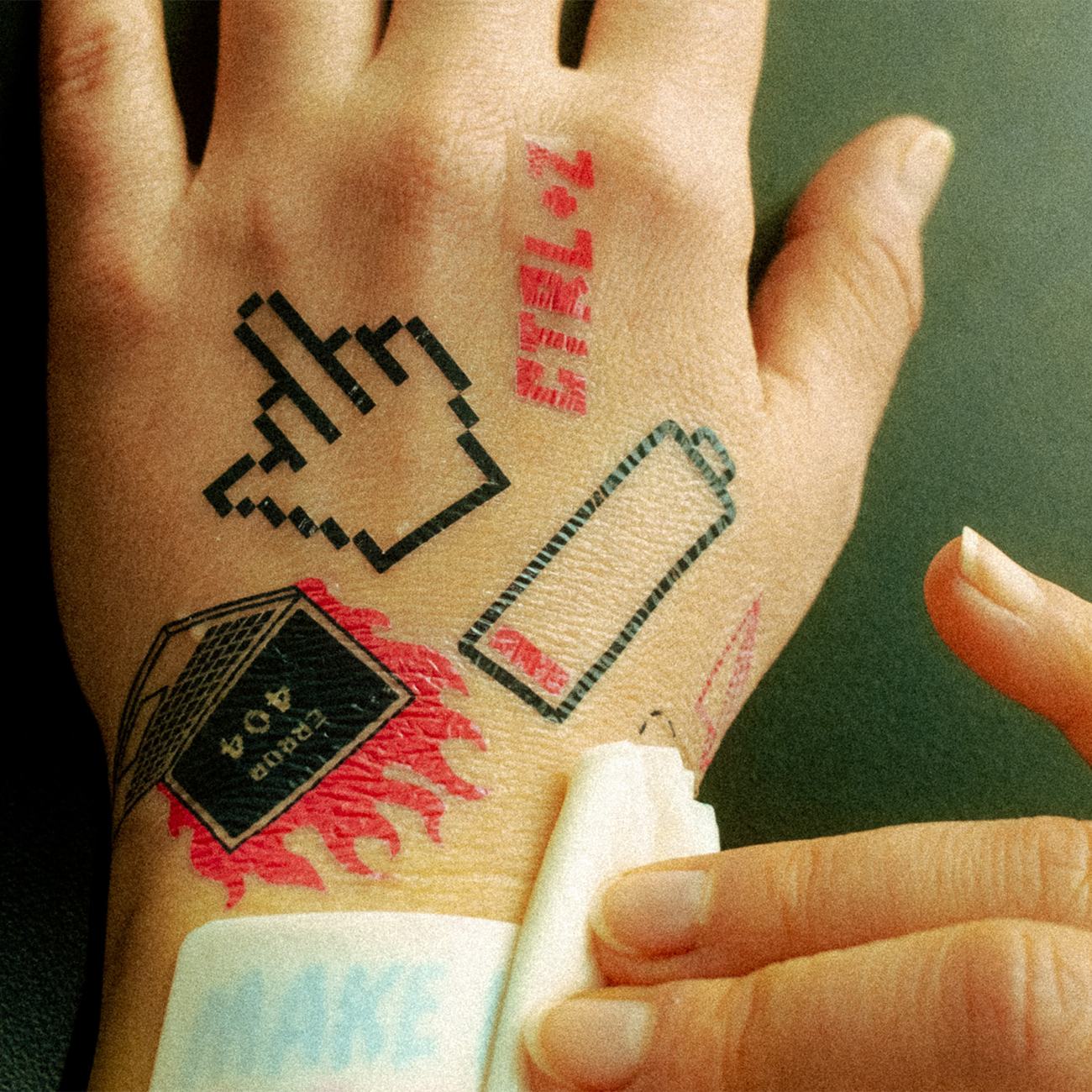 Hand with multiple temporary tattoos being applied using a damp cloth