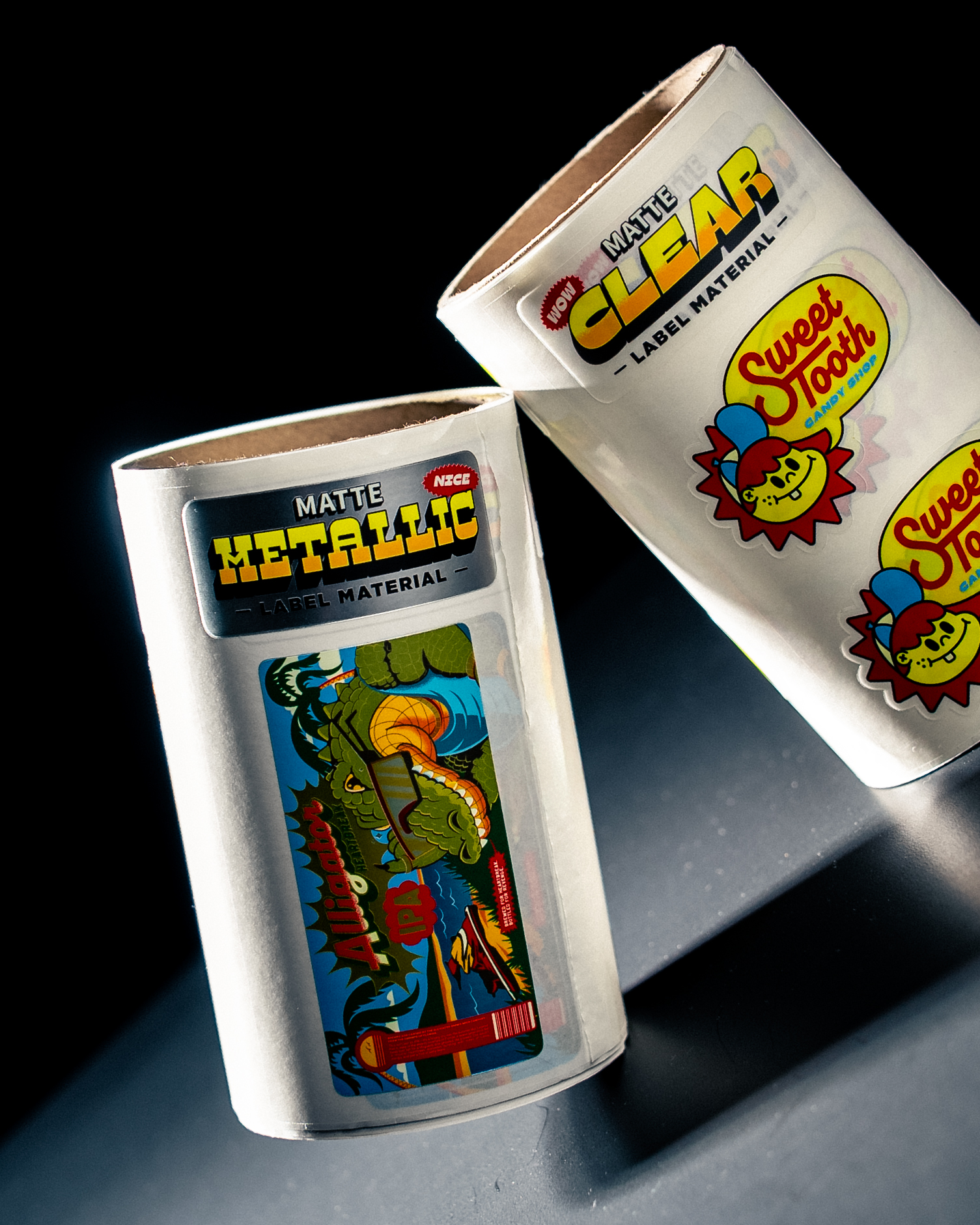Due rotoli di etichette campione con la scritta "Matte Metallic" e "Matte Clear", con un'etichetta Alligator IPA ed etichette Sweet Tooth Candy Shop
