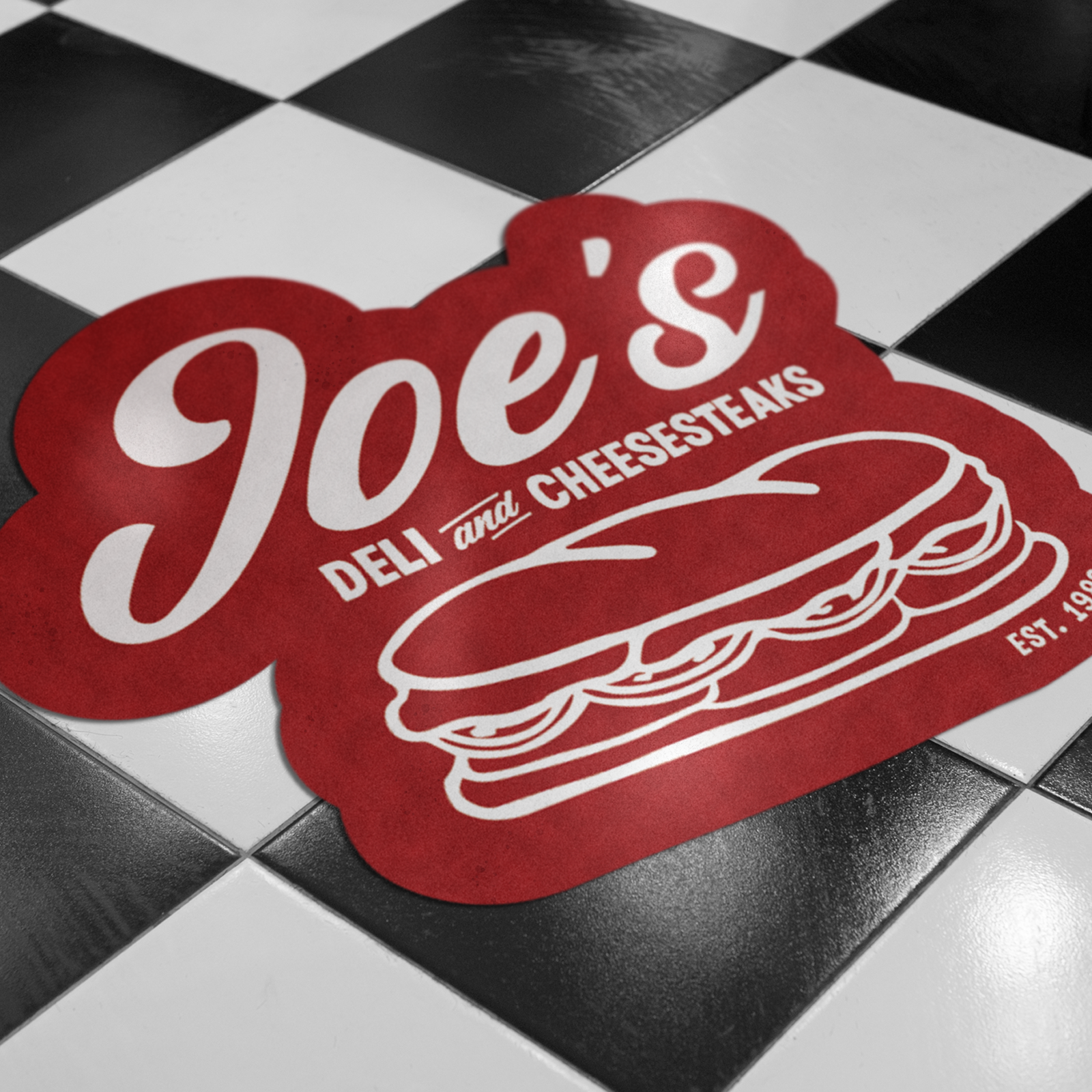 Decalcomania da pavimento personalizzata con il logo rosso di Joe's Deli and Cheesesteaks su un pavimento a scacchi bianchi e neri