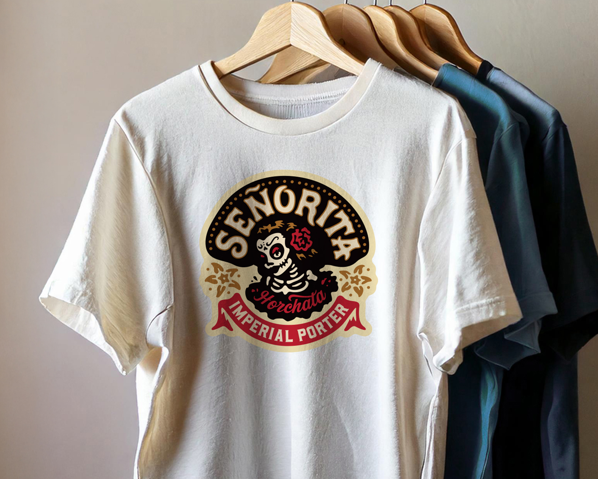 White T-shirt with "Señorita Horchata Imperial Porter" logo featuring a skeleton in a dress, hanging on a wooden hanger.
