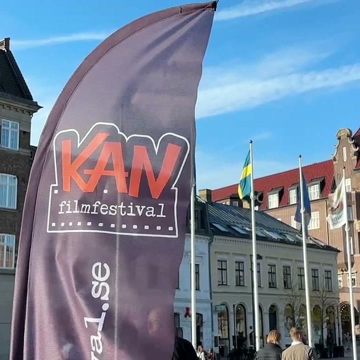 Bandiera a vela del KAN Film Festival davanti a edifici storici e bandiere in una piazza di Lund